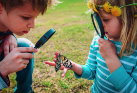 Unique outdoor activities for kids: kids observing butterfly with magnifying glass