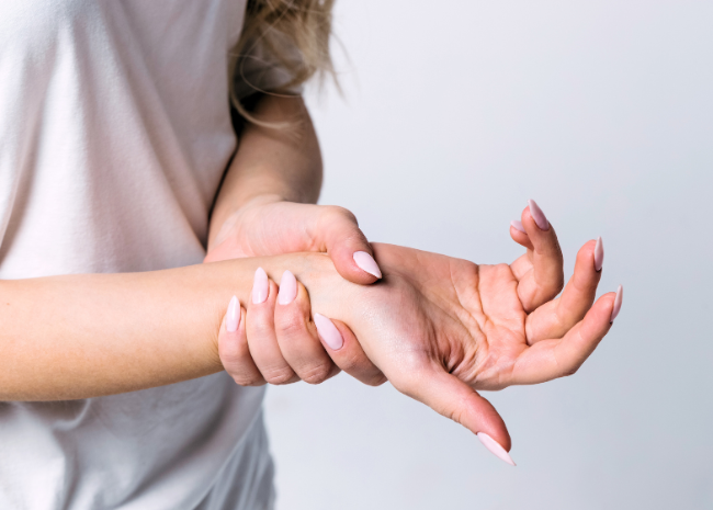 Woman experiencing symptoms of arthritis flare-up in hands, seeking management and treatment