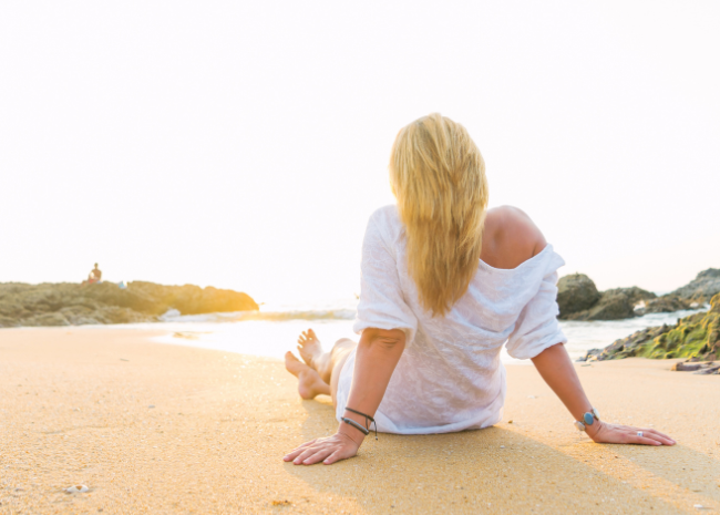 How to get rid of back pain: woman relaxing on beach happily