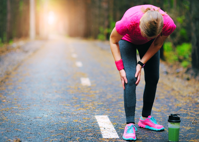 Knee Pain After Running: woman holding knee while on a run, injured knee in pain