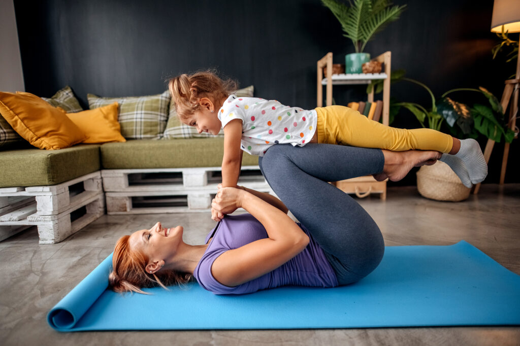 Busy mom fit exercise into schedule with daughter, doing yoga on yoga mat at home