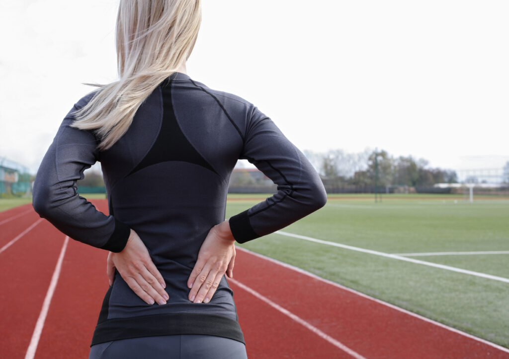 Female athlete struggling with sciatica and sciatic pain in back